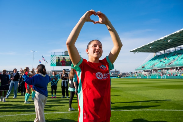 Izzy is showing a heart symbol with her hands.