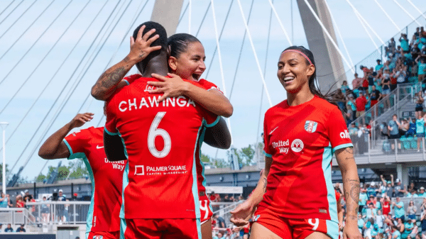 Photo of Bia, Chawinga, and Deb celebrating a goal.